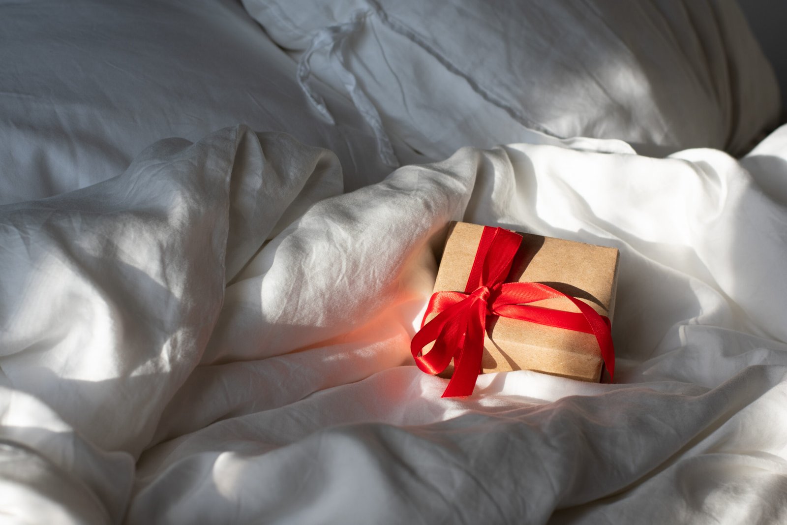 A gift with a red ribbon kept on a fluffy bedding.