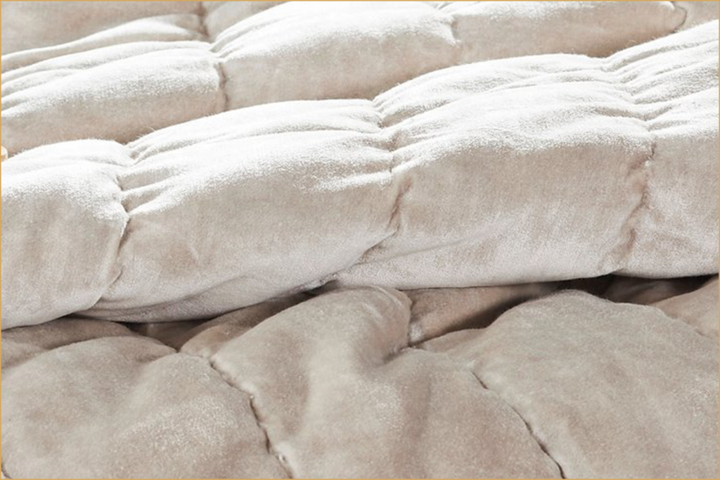 Close-up of a velvet quilt showing plush, raised quilting and soft sheen.